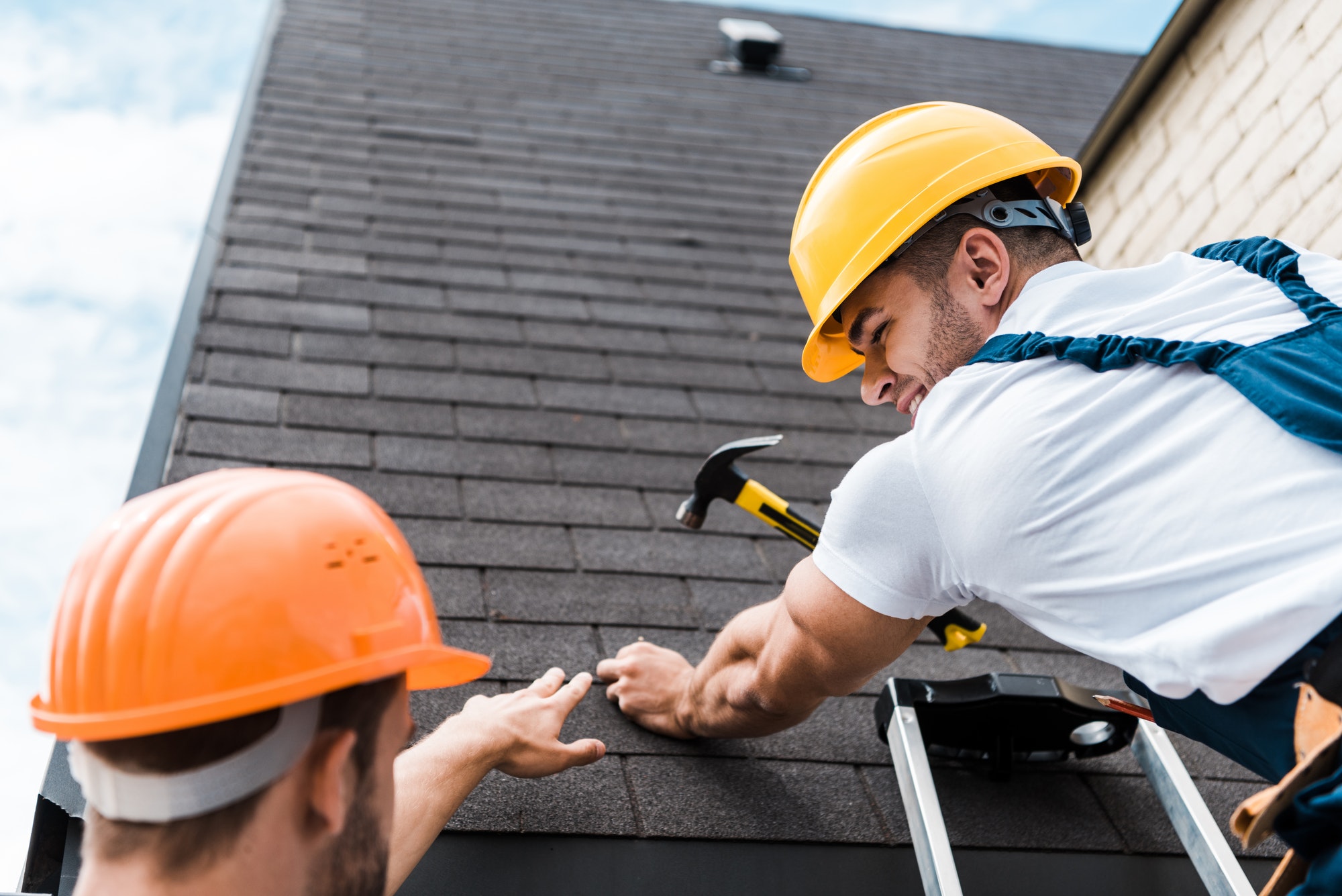 low angle view of repairman looking at coworker while holding hammer